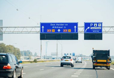 Den Helder, Hollanda - 27 Ağustos 2019: Den Helder ve Alkmaar 'a giden yolu gösteren mavi yol işaretli bir otoyol manzarası. Araçlar yolda giderken görülmüş ve olay yeri görüntülenmiş.
