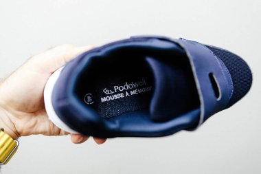 Paris, Fransa - 22 Haziran 2024: Bir çift Podowell marka rahat ayakkabıyı elinde tutan bir erkek ayak sağlığı sorunları olan yaşlılar için tasarlanmış, yastıklı tabanlar, destekleyici tabanlar ve parlak bir ayakkabı