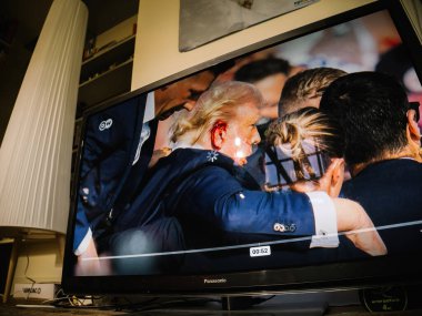 Londra, İngiltere - 14 Temmuz 2024: Yaşayan oturma odası televizyonu Bir suikast girişiminin canlı görüntüleri Donald Trump 'ı gösteriyor, bir ABD başkan adayı, kulağında kan ve küstah bir duruş