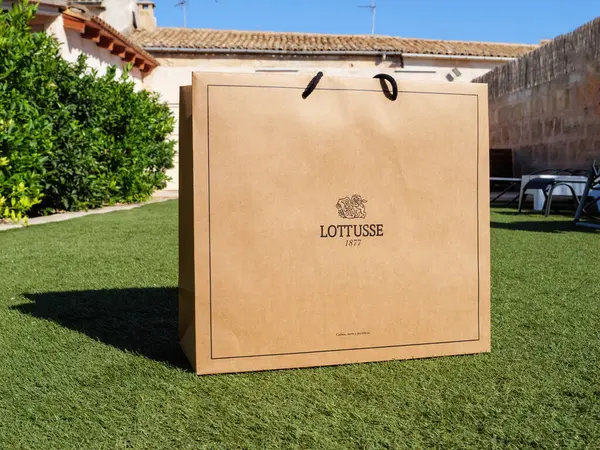 stock image Palma, Spain - Jul 11, 2024: A Lotusse 1877 Mallorca luxury shoes paper bag is placed in a luxurious garden within a finca in Mallorca, highlighting elegance and high-end style