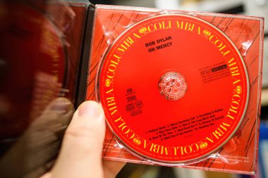 Paris, Fransa - 18 Mart 2024: Bob Dylans Oh Mercy 'nin SACD DSD diskini tutan bir erkeğin yakın çekimi, yüksek çözünürlüklü ses formatını ve ikonik albüm paketlemesini vurguluyor