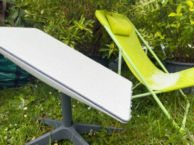 Frankfurt, Almanya - 18 Aralık 2024: Bir çocuk şezlongunun ve bahçedeki Starlink SpaceX anteninin üzerindeki dolu taşlarının görüntüsü, şiddetli hava koşullarının etkisini ve yansımasını gösteriyor