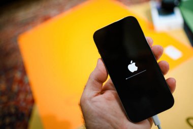 Paris, Fransa - 28 Ekim 2022: Apple logolu bir Apple iPhone 'u tutan bir erkek el ve ekranda bir ilerleme çubuğu, renkli bulanık bir yazılım güncellemesini gösteriyor
