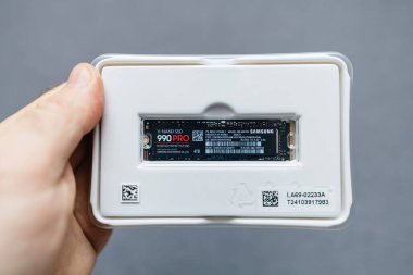 Paris, Fransa - 3 Nisan 2024: Yeni bir Samsung 990 Pro 4TB NVMe diski tutan bir erkek el gri bir arkaplana karşı ultra hızlı veri erişimi için, boks yapma sürecini yakalıyor ve gelişmiş