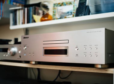 Paris, Fransa - Ağustos 1, 2024: Pioneer PD-50 AE Super Audio CD, MQA ve SACD CD kompakt disk oynatıcılarının arka planda çeşitli diskleri olan yan görüntüsü, gelişmiş bir vitsoe rafını vurguluyor