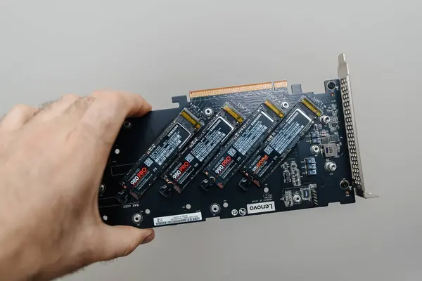 stock image Paris, France - Apr 3, 2024: A male hand holding a ThinkStation OCI NVMe expansion card with four ultra-fast disks, including Samsung 880, 990, and 970 Evo, highlighting advanced storage technology