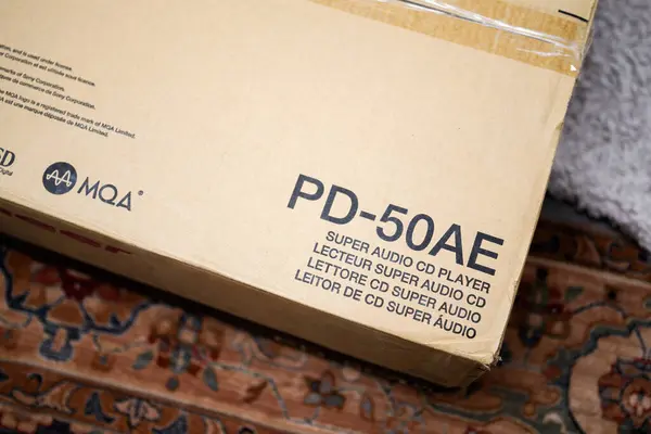 stock image Paris, France - Aug 1, 2024: A cardboard box of a luxury Pioneer PD-50 AE Super Audio CD and MQA CD player placed on a living room carpet, highlighting the packaging and anticipation of high-end audio