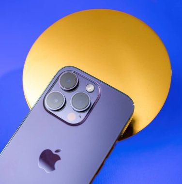 Paris, Fransa - Sep 29, 2022: Apple 'ın son iPhone Pro' su, gerçek altından yapılmış, mavi arka planda kurulmuş, modern teknolojiyle zarif bir arkaplanı birleştiren altın yuvarlak bir destekte sergileniyor.