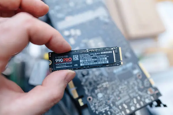 stock image Paris, France - Apr 3, 2024: A male hand holds a Samsung 990 Pro V-NAND SSD NVMe ultra-fast disk above the circuit board during the upgrade of a customers workstation laptop, focusing on the