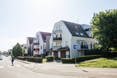 Bir dizi Fransız apartmanı ve karşıdan karşıya geçen bir kadın, emlak yatırımını ve şehir yaşamını temsil ediyor.