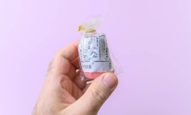 Paris, Fransa - 7 Mart 2024: Japon oyuncak figürü sarılmış, baskı talimatları verilmiş, pastel arka plan üzerine kurulmuş, basit ama büyüleyici bir tasarımı vurgulayan bir erkek el.