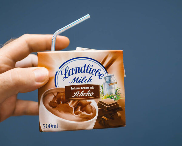 Berlin, Germany - Oct, 22, 2019: A hand holding a Landliebe chocolate milk carton with a straw inserted, emphasizing the packaging design and branding of this popular German beverage