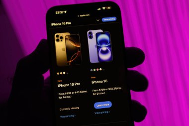 Paris, Fransa - Sep 8, 2024: iPhone 16 Pro Max 'i elinde tutan bir erkeğin dikey çekimi, iPhone 16 Pro ve iPhone 16 modelleri arasında bir karşılaştırma sayfası görüntülüyor
