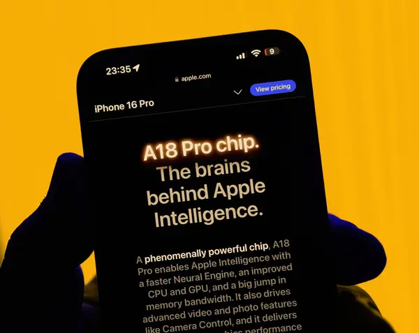 stock image Paris, France - Sep 8, 2024: Vertical shot of a male hand holding the iPhone 16 Pro Max with a yellow background, featuring the slogan A18 Pro Chip: The Brains Behind Apple Intelligence, highlighting