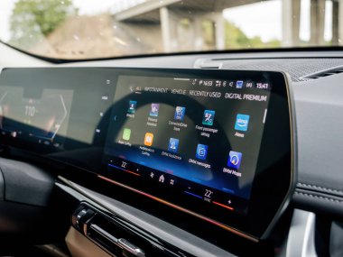 Munich, Germany - Sep 8, 2024: The curved display of a BMW iX1 electric car shows all the applications while driving under a bridge, emphasizing the vehicles advanced dashboard technology and user clipart