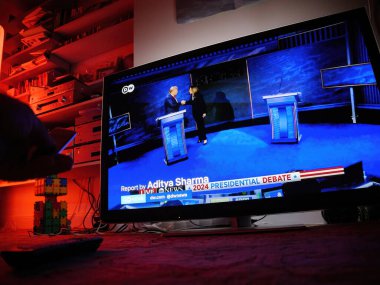 Paris, Fransa - 11 Eylül 2024: Oturma odası TV ekranı, Kamala Harris ve Donald Trump arasında ön planda uzaktan kumandalı bir adamla el sıkışırken başkanlık tartışmasını gösteriyor