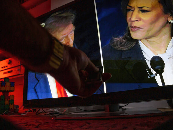 Paris, France - Sep 11, 2024: A living room TV screen shows a male hand holding a remote as a presidential debate between Kamala Harris and Donald Trump unfolds, with Kamala Harris appearing focused