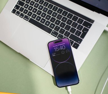 Paris, Fransa - 29 Eylül 2022: Pürüzsüz bir iPhone 16 Pro ve MacBook Pro yeşil bir masaya yerleştirilmiş, modern ve şık bir ortamda elmaların son teknolojisini sergiliyor.