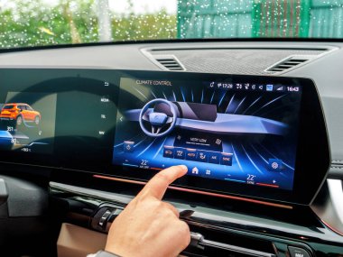 Münih, Almanya - Sep 9, 2024: Bir kadının eli BMW iX lüks elektrikli SUV 'nin AC kontrollerini işaret ederek aracın gelişmiş iklim kontrol sistemini ve modern iç tasarım sistemini vurguluyor