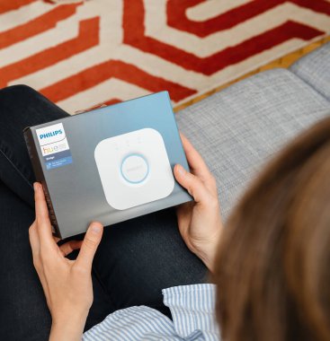 Paris, Fransa - 16 Ağustos 2019 Philips Hue Smart Köprüsü 'nü tutan rahat bir kadın evindeki tüm lambaları kontrol etmek için kutuyu açmaya hazırlanıyor..