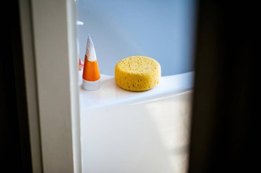 Banyo süngeri, banyo düzenini gösteren küvetin köşesindeki şampuan ya da duş jelinin yanına yerleştirilmiş..