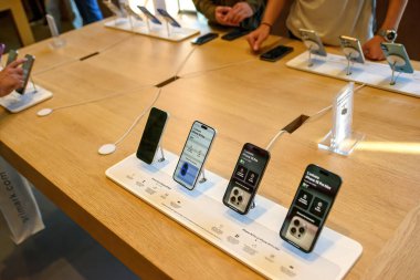Paris, Fransa - 20 Ekim 2024: iPhone 16 Pro ve iPhone 16 Plus modelleri Apple Store 'da sergilenirken, erkek müşteriler arka planda telefonları test ediyor
