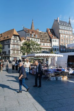 Strasbourg, Fransa - 20 Sep 2024: Yaşlılar ve yetişkinler alışveriş yaparken, Strasbourg 'un merkezindeki Place Kleber' da giyim pazarı tezgahı. Hareketli meydanda hareketli bir moda ve yerel ticaret manzarası