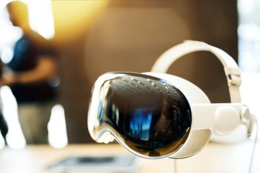Paris, Fransa - 20 Ekim 2024: Apple Vision Pro dijital içeriği fiziksel dünyayla harmanlayarak kahraman nesne olarak sergilendi. Arka planda dahi bir işçinin olduğu bir Apple mağazasında sergileniyor.