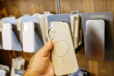 Paris, Fransa - 20 Eylül 2024: Bir Apple mağazasının arka planında birden fazla kasa bulunan Beats 'in iPhone 16' sı için erkek elinde sarı plastik çanta bulunuyor