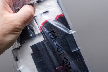 Kullanılmış bir yazıcı bakım kartuşunun plastik bir torbaya kapatılıp, ambalajda görünür mürekkep ve geri dönüşüm sembolleri gösterilmesi