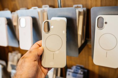 Paris, Fransa - 20 Sep 2024: iPhone 16 Pro Max için erkek eli, mıknatıslarla şarj etme halkalarını, POV görünümlü, iPhone 16 Pro Max için ses plastiğini tutuyor