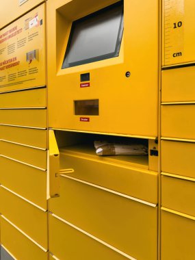Kehl, Almanya - 24 Nisan 2024: Sarı DHL paket dolabı ve açık bir bölmesi var, bir teslimat paketini gösteriyor, posta ve paket teması için ideal