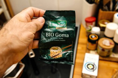 Paris, Fransa - 19 Temmuz 2020: Arka planda mutfak baharatları ve tofu ile Lien Ying BIO Goma organik kavrulmuş susam tohumlarını tutan bir erkeğin yakın çekimi