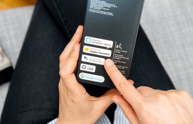 Paris, France - Aug 16, 2024: A woman holds the Philips Hue Bridge for smart lighting while a man points to the Apple HomeKit compatibility text on the cardboard box clipart