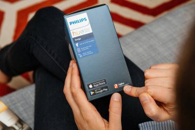 Paris, Fransa - 16 Ağustos 2024: Bir kadın Philips Renk paketinde akıllı köprü aydınlatma aygıtı içeren Zigbee sertifikalı ürün metnini işaret ediyor