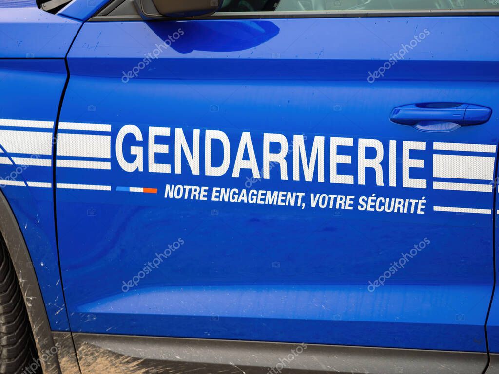 A close-up of the side of a blue French Gendarmerie vehicle, featuring the official logo and the message Notre engagement, votre securite, symbolizing law enforcement and public safety in France