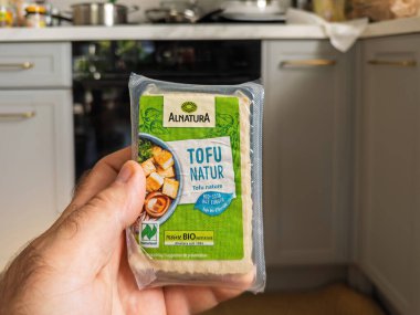 Paris, Fransa - Sep 19, 2024: Bir el, Avrupa 'da soya fasulyesinden yapılan sağlıklı, vejetaryen bir seçeneğin altını çizen mutfakta bir Alnatura organik tofu paketini tutuyor