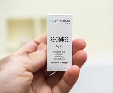 Paris, France - Apr 8, 2020: A close-up of a hand holding a Clarins Re-Charge sleep mask, a skincare product for relaxing and rejuvenating all skin types, ideal for nighttime use