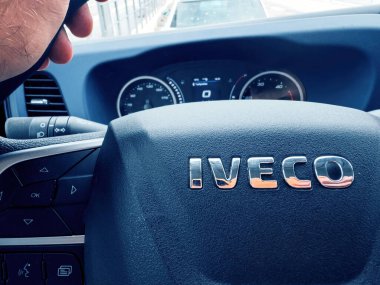 Paris, France - Sep 17, 2024: Close-up of Iveco truck steering wheel with dashboard view, capturing the controls, gauges, and drivers hand in motion clipart