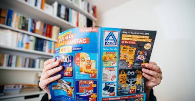 Frankfurt, Germany - Nov 3, 2024: Person reading an Aldi flyer with Halloween-themed products and discounts on groceries, showcasing seasonal deals and budget-friendly offers clipart