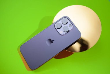 Frankfurt, Almanya - Sep 29, 2022: iPhone 15 Pro Max 'in arka görüntüsü, metalik dairesel bir objeye yerleştirilmiş, canlı yeşil bir arkaplan, parlak ve parlak bir tasarım.