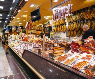 Palma, İspanya - 8 Temmuz 2024: Palma de Mallorca 'daki Mercat de l Olivar' da, bir erkek satılık çeşitli et ürünleri seçerek piyasaların zengin aşçılık sunumlarını sergiliyor..