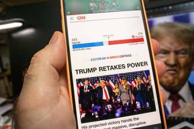 Paris, Fransa - 6 Kasım 2024: CNN 'in 2024 seçim sonuçlarıyla Trump Retakes Power manşetini gösteren akıllı telefon ekranı. Trump, Harris 'i Trump' ın bilgisayardaki arkaplan görüntüsüyle yönetiyor.