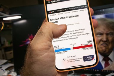 Paris, Fransa - 6 Kasım 2024: Bir akıllı telefon CNN 2024 başkanlık seçim projeksiyonunu Trump 'ın önde gelen Harris' i Trump 'ın arka plan görüntüsüyle göstermektedir