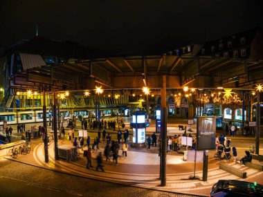 Strasbourg, Fransa - 23 Aralık 2024: Strasbourg 'daki Place de lHomme de Fer' in gece görüşü, aydınlatılmış yıldızlar, yoğun bir tramvay istasyonu ve insanlar meydanda toplandı