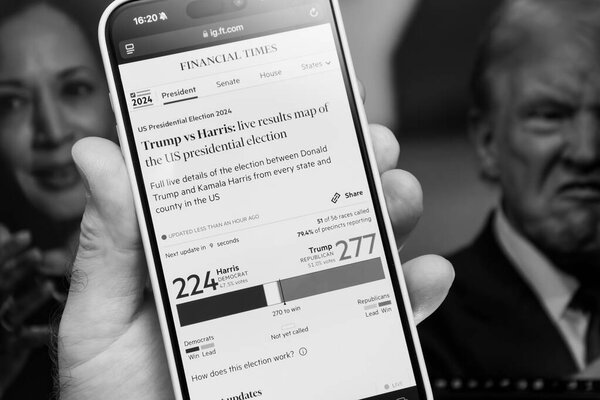 Paris, France - Nov 6, 2024: A black-and-white image shows a smartphone in a hand displaying Financial Times 2024 election results, with Trump leading Harris and background images of both candidates