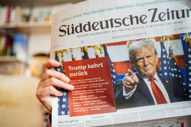 Paris, Fransa - 7 Kasım 2024: Samimi bir oturma odasında Suddeutsche Zeitung okuyan kadının yakın çekimi, Donald Trump 'ın seçim zaferi ve ABD politikasına dönüşüyle ilgili manşet