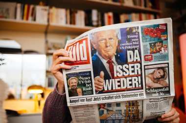 Paris, Fransa - 7 Kasım 2024: Samimi bir oturma odasında Alman magazin gazetesi Bild okuyan kişi, Donald Trump 'ın ABD Başkanı olarak dönüşünü kapsayan Da isser Wieder manşeti