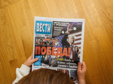 Paris, Fransa - 7 Kasım 2024: Pobeda manşetiyle Sırp Vesti gazetesini elinde tutan meraklı çocuk - Donald Trump seçim galibiyeti ile ilgili zafer, güncel olaylarla ilgilendiğini gösteriyor