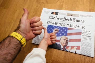 Paris, Fransa - 7 Kasım 2024: Meraklı çocuk ve yetişkin her ikisi de New York Times 'ın baş sayfasına Trump Storms Back manşetiyle destek veriyorlar.